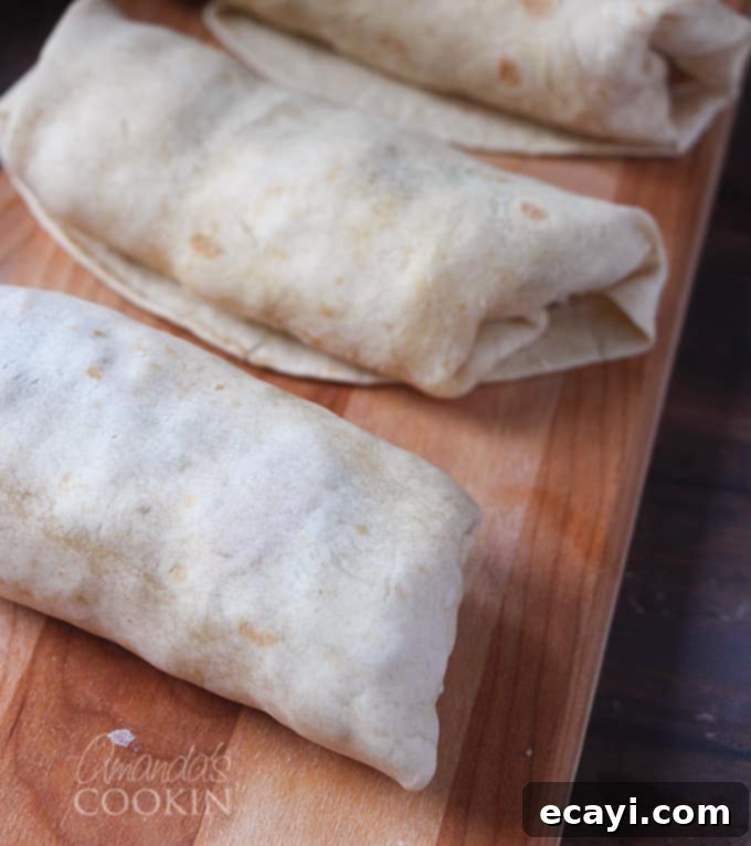 Sunrise Burritos 5 Several breakfast burritos, tightly rolled and wrapped in wax paper, ready for freezing. A note reads: 'Roll them up and pop them in the freezer. So simple and so good!'