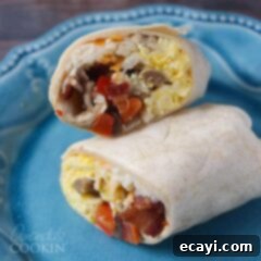 Sunrise Burritos 6 A perfectly wrapped breakfast burrito, sliced in half, showcasing its hearty fillings, presented on a vibrant blue plate.