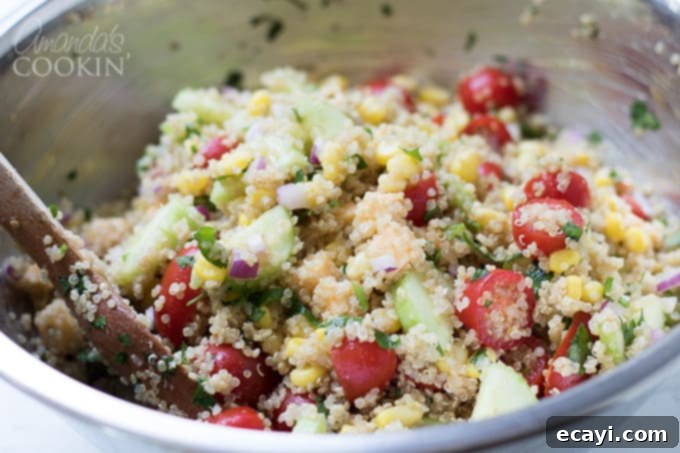 Garden Fresh Summer Quinoa Delight 7 Tossing the quinoa and vegetables together in a large bowl, ensuring an even distribution of all components for the summer vegetable quinoa salad.