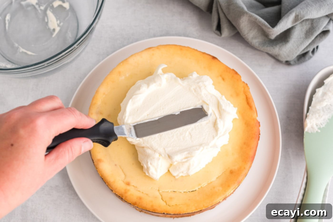 Regal Trifle Cheesecake 13 An icing spatula smoothly spreading freshly whipped cream over the top of the chilled English Trifle Cheesecake.