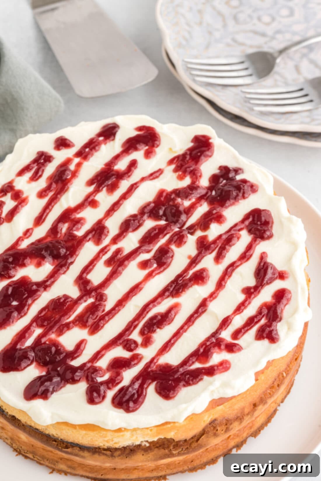 Regal Trifle Cheesecake 3 An inviting overhead view of a whole English Trifle Cheesecake, beautifully garnished with whipped cream and a raspberry drizzle, ready to be served.