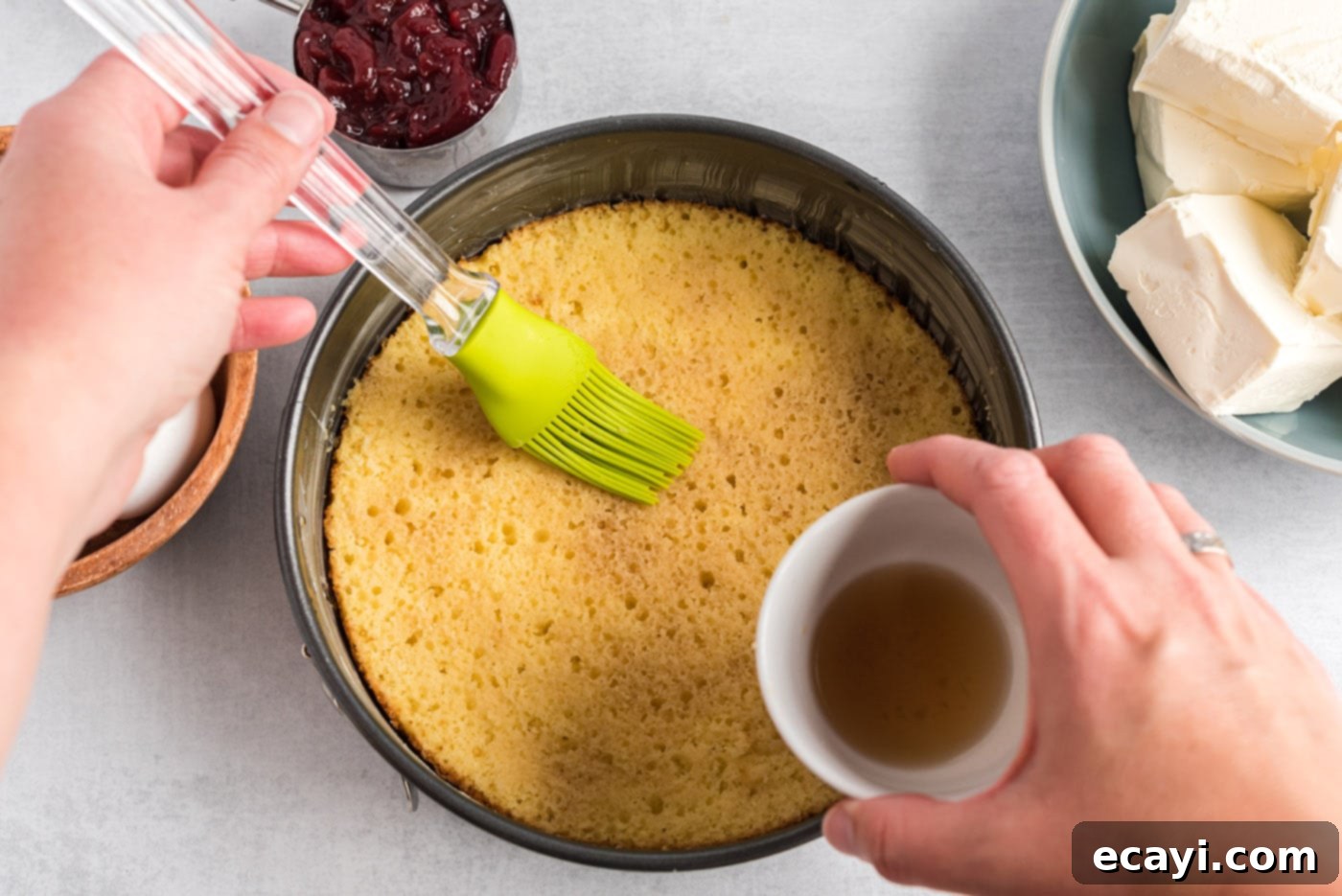 Regal Trifle Cheesecake 6 A pastry brush applying cream sherry onto the yellow cake layer pressed into a springform pan.