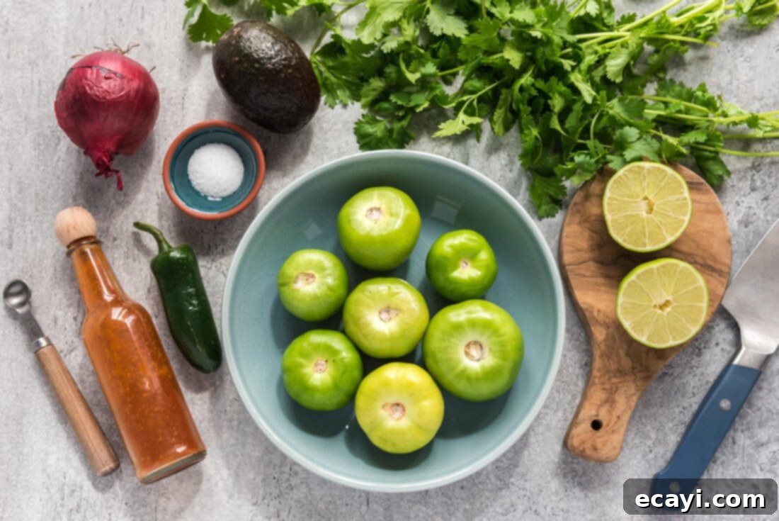 Vibrant Tomatillo Avocado Onion Salsa 4 Ingredients for Tomatillo Onion Avocado Salsa laid out on a cutting board, including tomatillos, avocado, onion, cilantro, and lime.