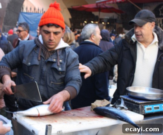 A worker at La Pescheria, fish market in Catania, Sicily A dedicated worker at La Pescheria, skillfully preparing fresh fish for customers in Catania, Sicily
