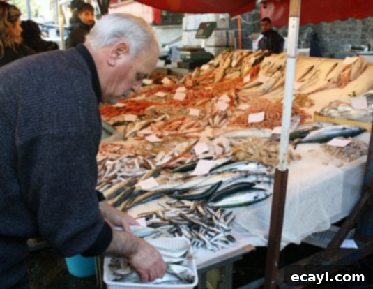 A worker at his stall at La Pescheria, fish market in Catania, Sicily A fishmonger proudly presenting his catch at his bustling stall in La Pescheria, Catania, Sicily