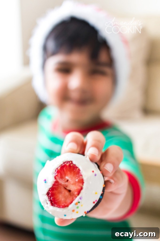 Chocolate covered Strawberry Christmas Trees have an Oreo cookie base, perfect finger food. Delicious strawberries look like festive little Christmas trees! little boy holding out a chocolate covered strawberry with a bite out of it