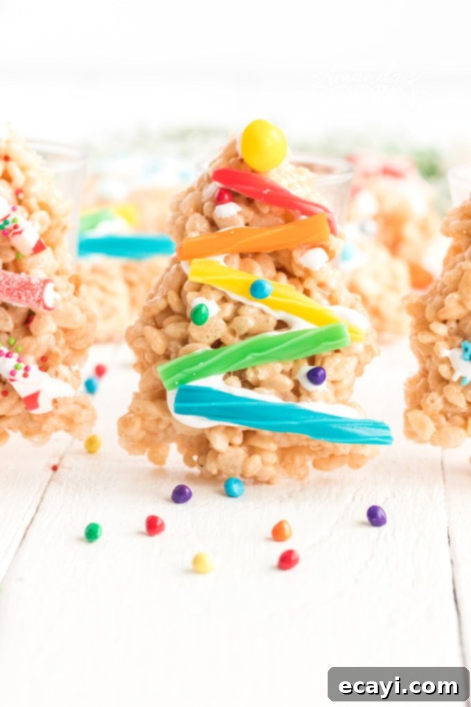 Make Christmas Tree Rice Krispie Treats with the kids. Rice Krispies, marshmallows, and candy decorations make adorable Christmas trees! rice krispie treat christmas tree decorated with candies