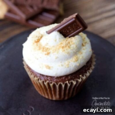 35+ Delicious Cake Mix Recipes 3 A close up of a s'mores cupcake topped with a Hershey bar piece and toasted marshmallow, evoking campfire nostalgia.