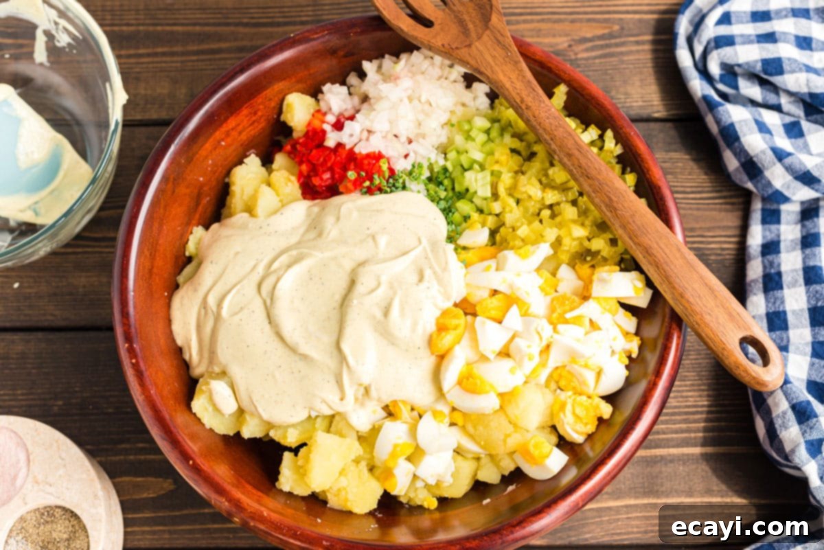 Mom's Classic Potato Salad 7 Creamy dressing poured over the mixed potato salad ingredients, ready for tossing.