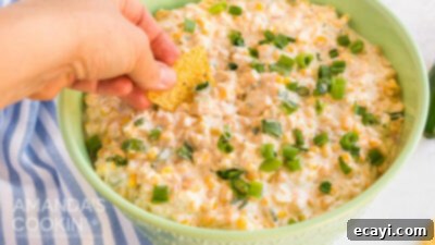 Fiesta Corn Dip 14 Hand dipping tortilla chip into creamy corn dip, ready to eat