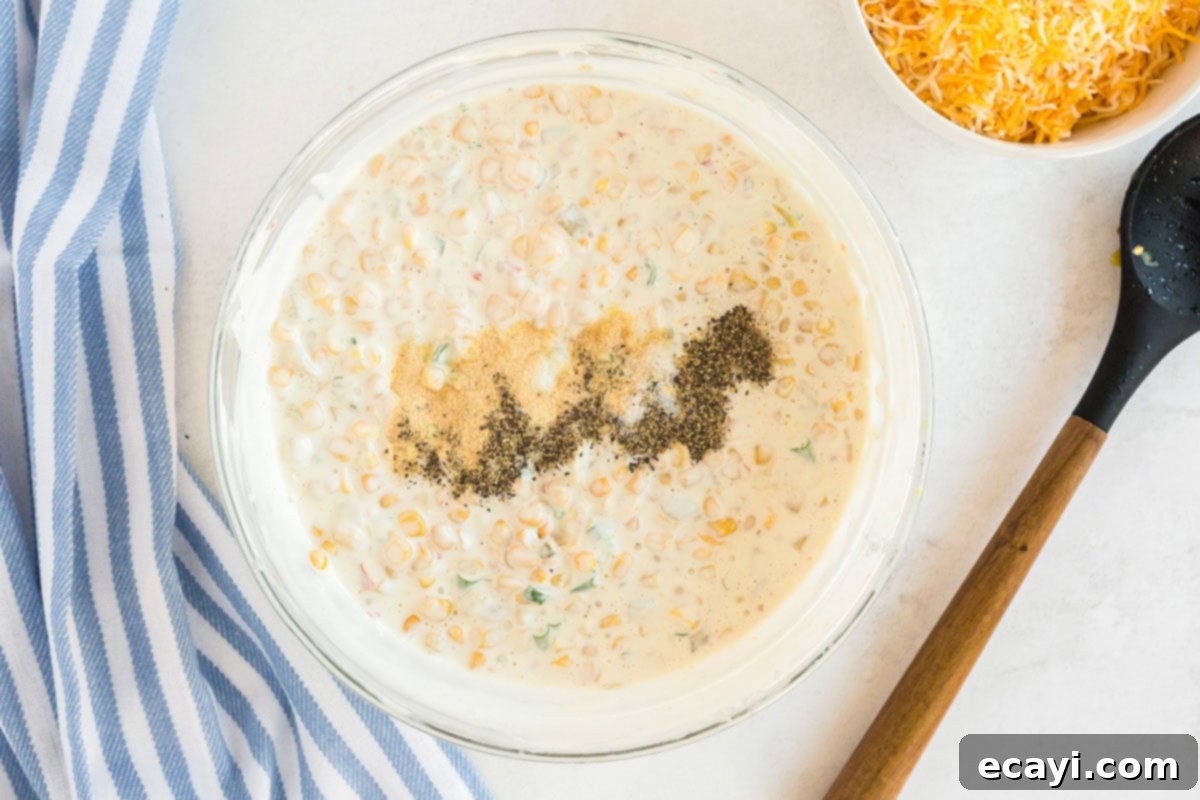 Fiesta Corn Dip 7 Overhead view of a bowl of creamy corn dip, with seasonings visibly sprinkled on top before being mixed in