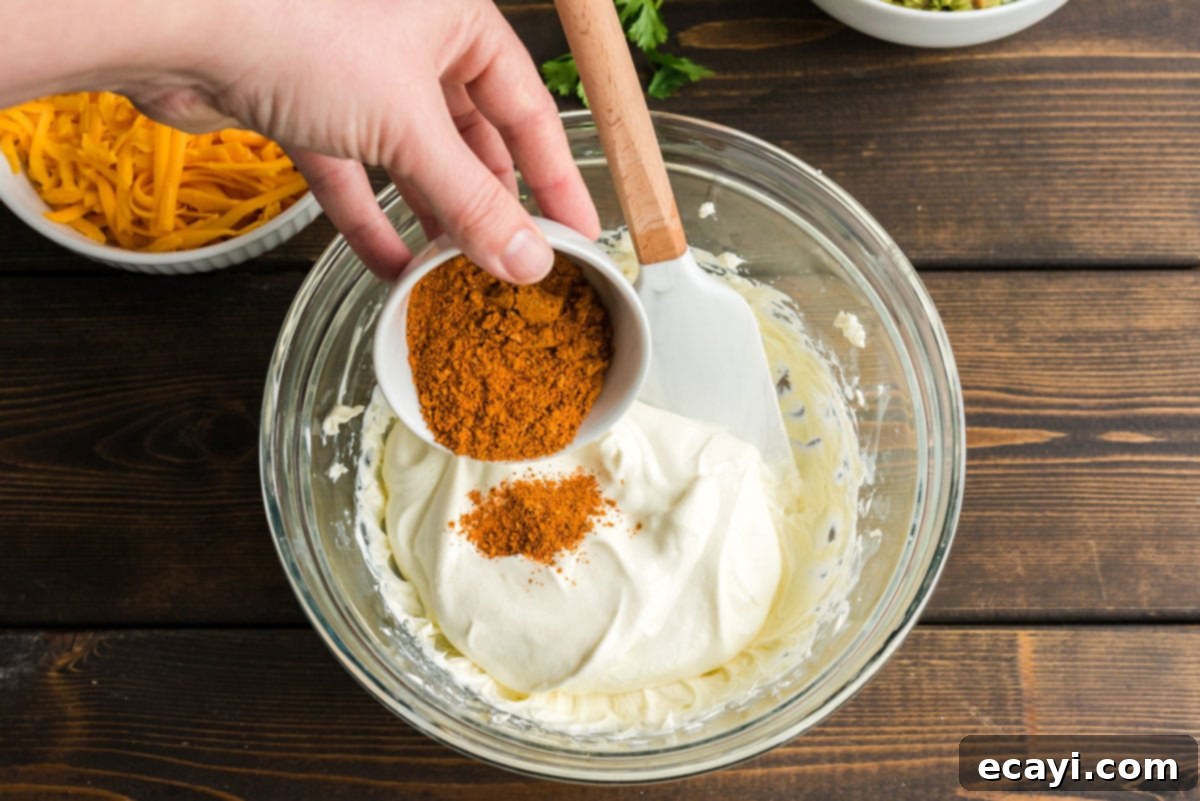 Ultimate Taco Dip 5 Adding taco seasoning to a bowl of sour cream and beaten cream cheese for the flavorful middle layer of the dip
