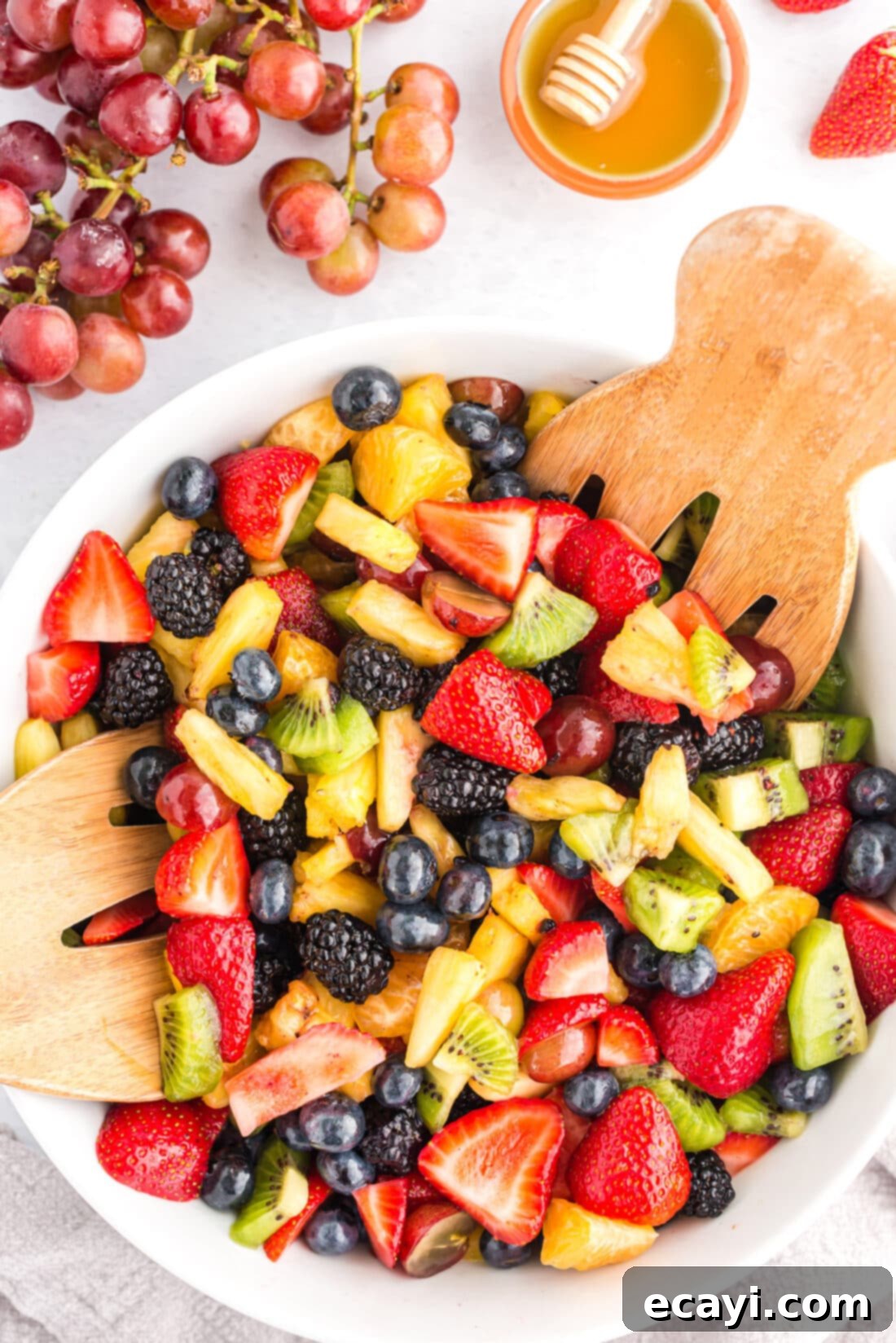 Our family's go-to fruit salad recipe, always a favorite at every holiday gathering. Large wooden bowl filled with colorful fresh fruit salad, with two wooden serving spoons resting on the side.