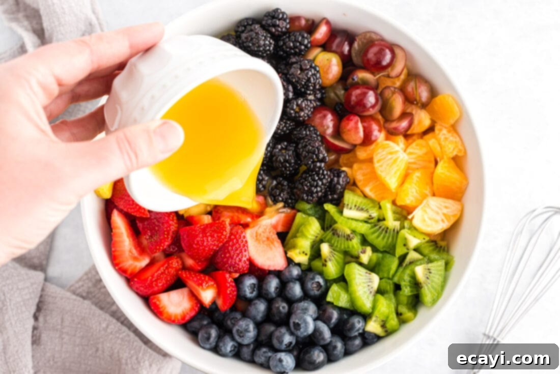 Nature's Sweet Bowl 4 Hands gently tossing mixed fresh fruits in a large clear bowl with a dressing.