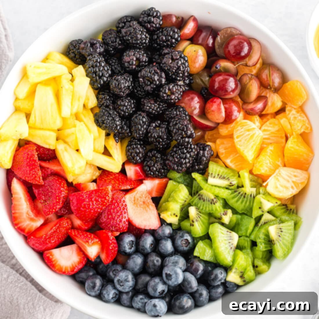 My cousin insists on having fruit salad at every holiday. This is our family's go-to recipe and it's always a favorite. Assortment of vibrant fresh fruits in a large glass bowl, ready to be served as a fruit salad.