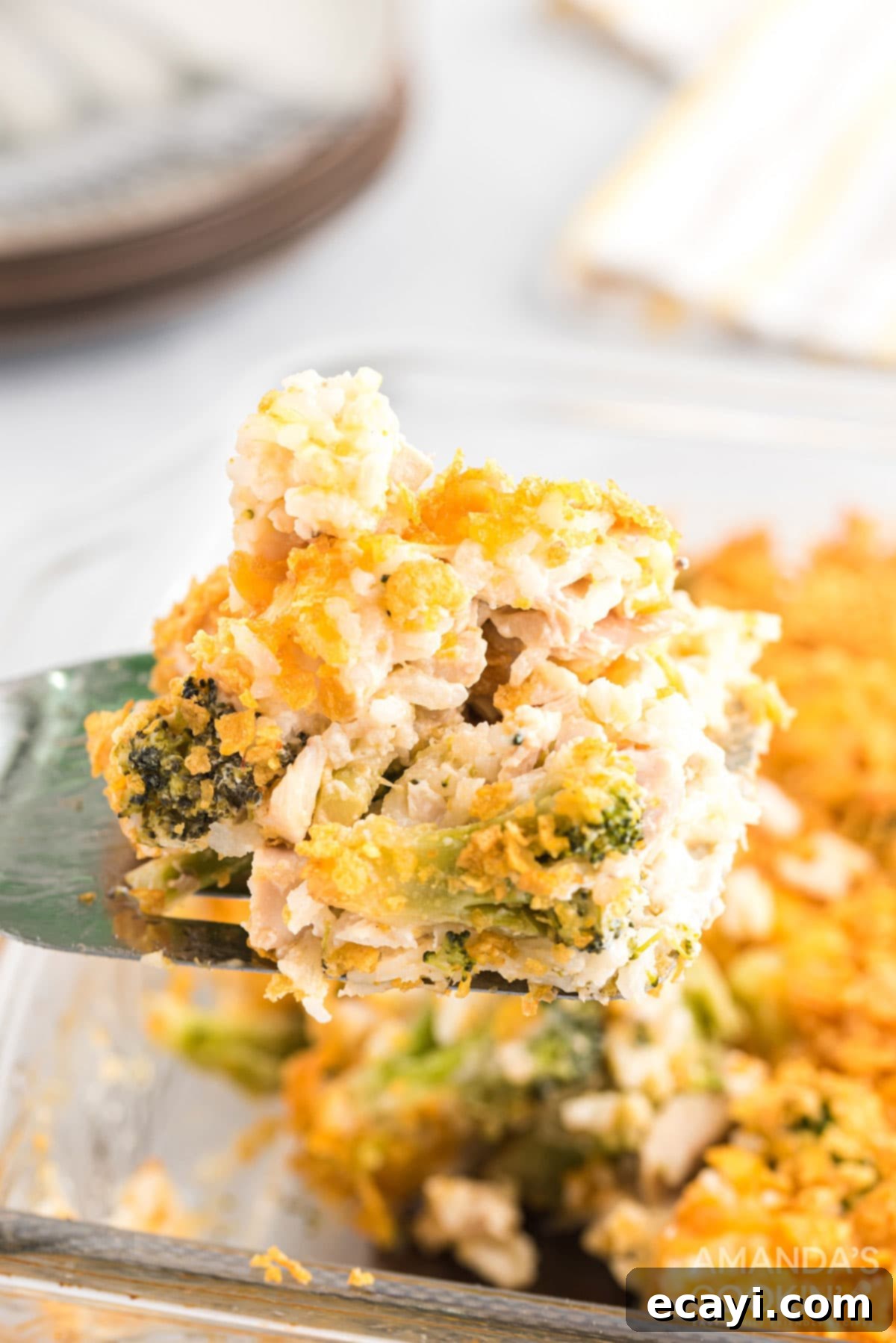Pure comfort food, this Chicken Broccoli Rice Casserole uses only 8 ingredients, and 40 minutes is all you need to put this delicious dinner on the table. Serving spatula lifting a portion of Chicken Broccoli Rice Casserole