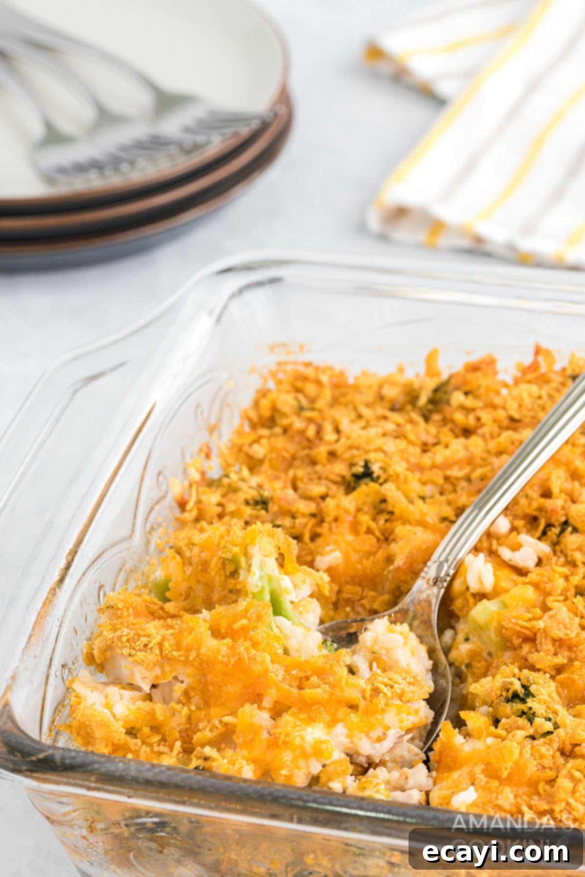 Pure comfort food, this Chicken Broccoli Rice Casserole uses only 8 ingredients, and 40 minutes is all you need to put this delicious dinner on the table. Glass baking dish of Chicken Broccoli Rice Casserole with a serving spoon, ready to eat