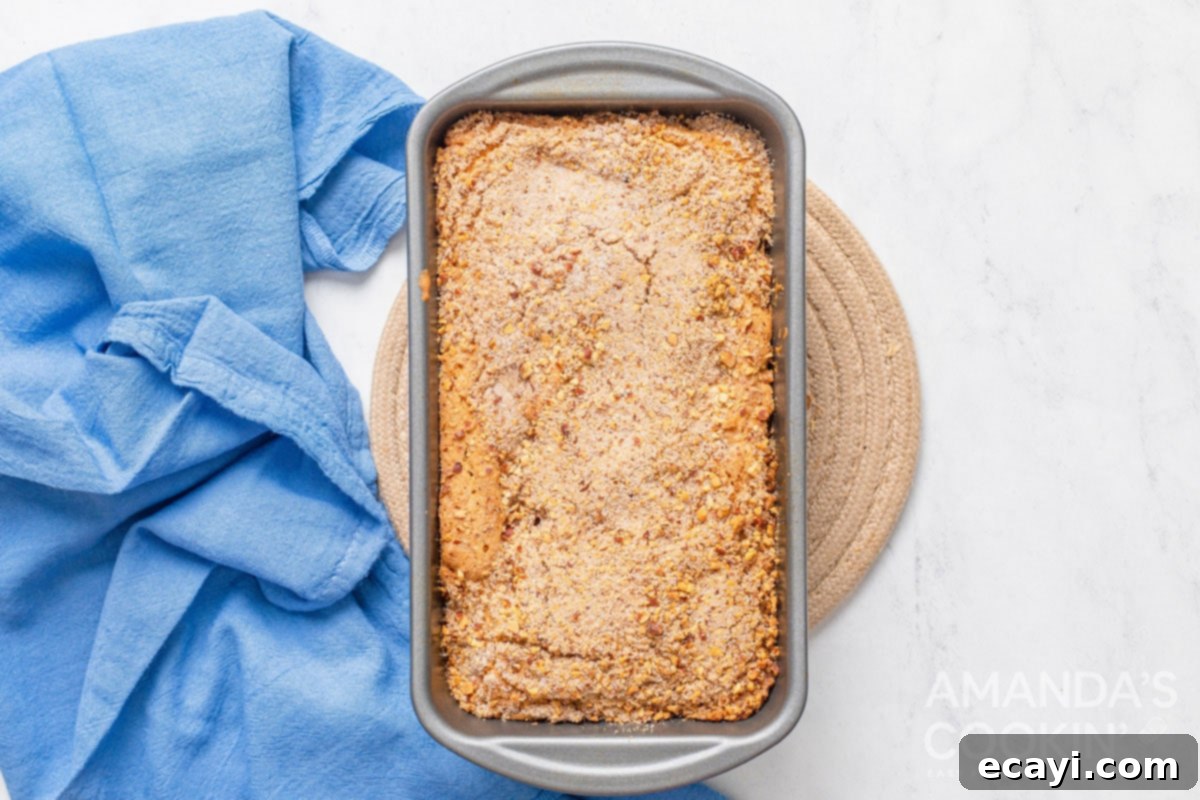 Golden Peach Loaf 7 A golden brown, freshly baked loaf of peach quick bread still in its pan, having just come out of the oven, indicating it's ready for cooling.