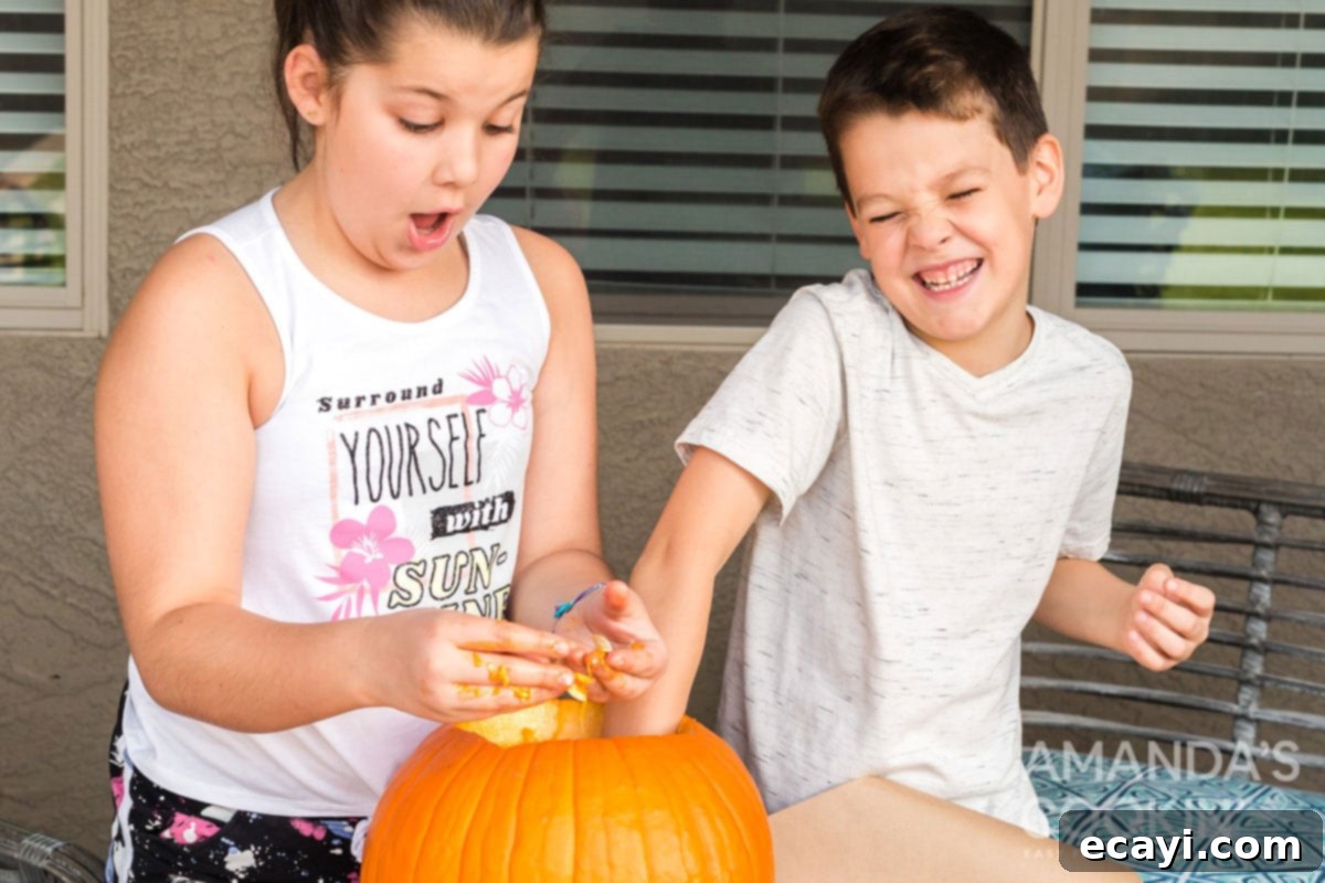 Kids having fun cleaning out a pumpkin Children happily scooping out pumpkin guts and seeds from a large carved pumpkin, making a fun and slightly messy Halloween tradition.