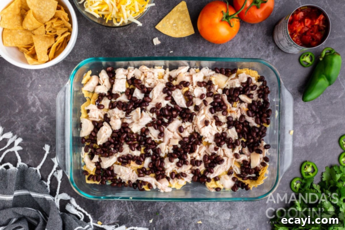 Fiesta Chicken Bake 4 Layer of black beans and diced chicken in the casserole dish over tortilla chips