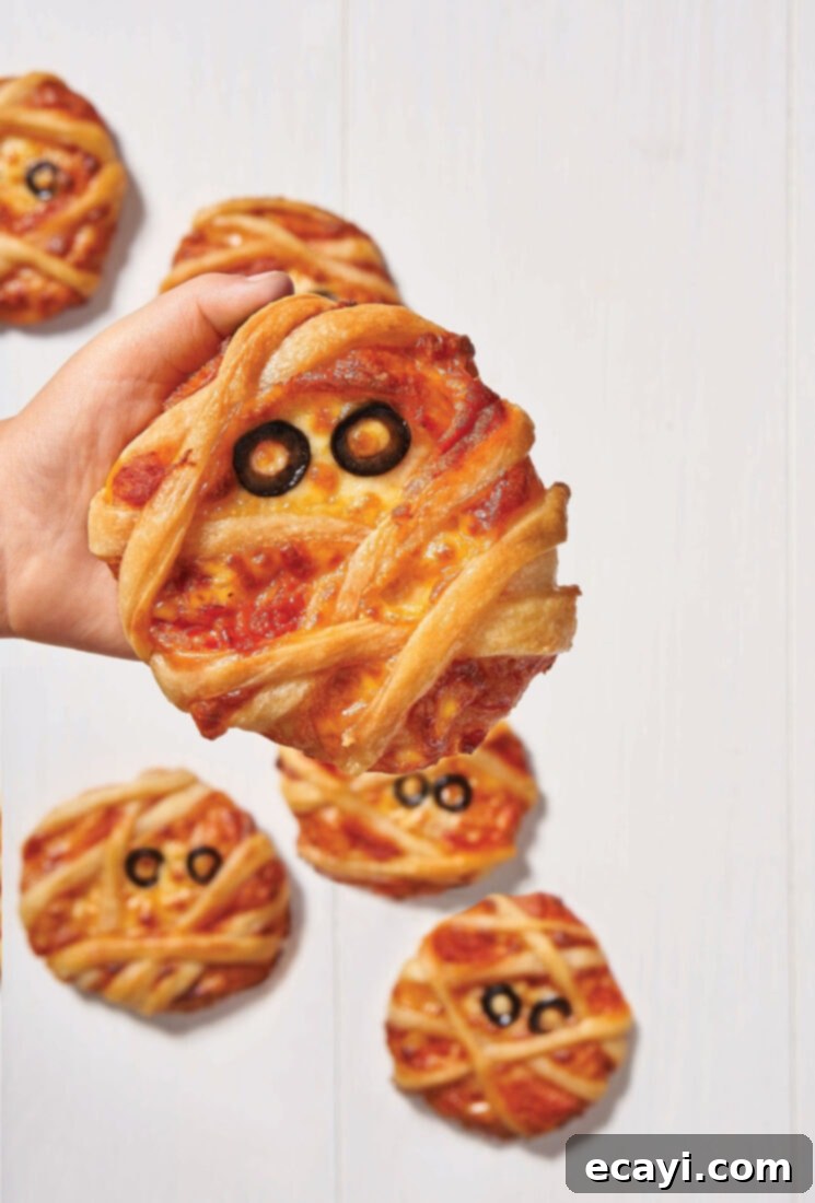 Monster Munchies 3 Child happily holding a mini mummy pizza, a simple yet charming Halloween treat