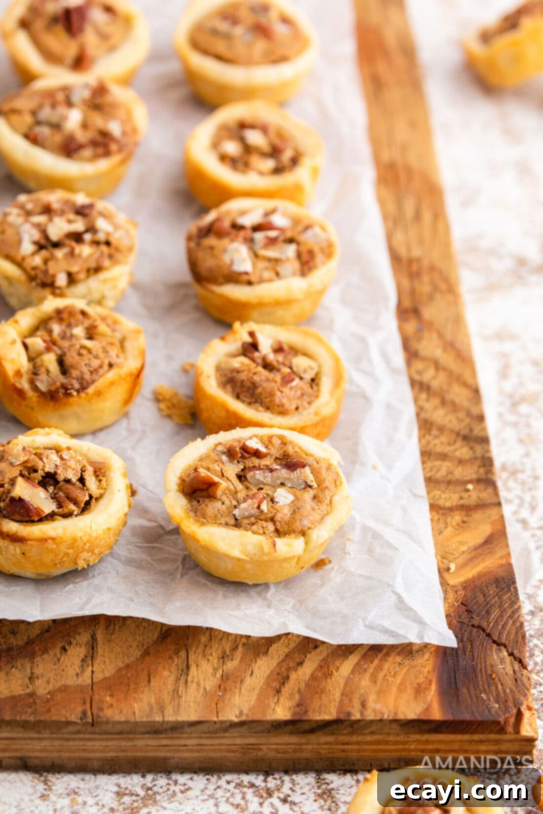 Bite-Sized Pecan Delights 3 pecan tassies on a wood cutting board