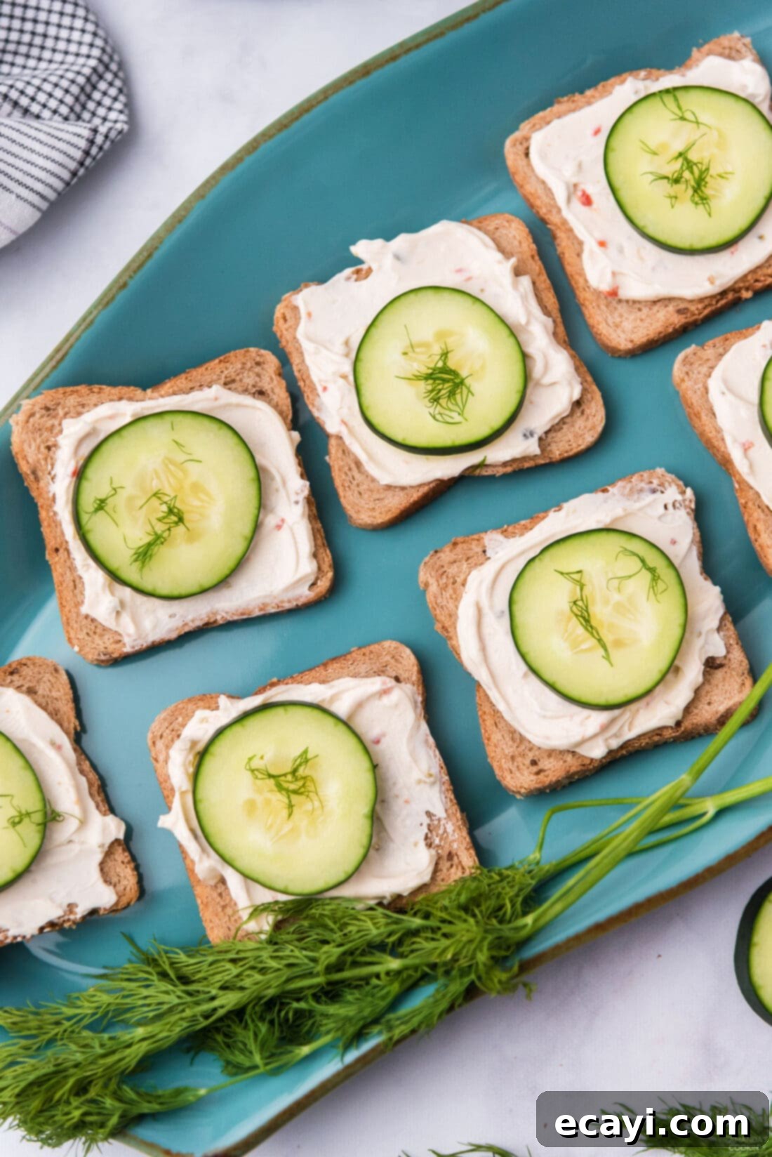 Delicate Cucumber Finger Sandwiches 3 Close-up of freshly made mini cucumber sandwiches arranged neatly on a vibrant blue platter, showcasing their enticing presentation.