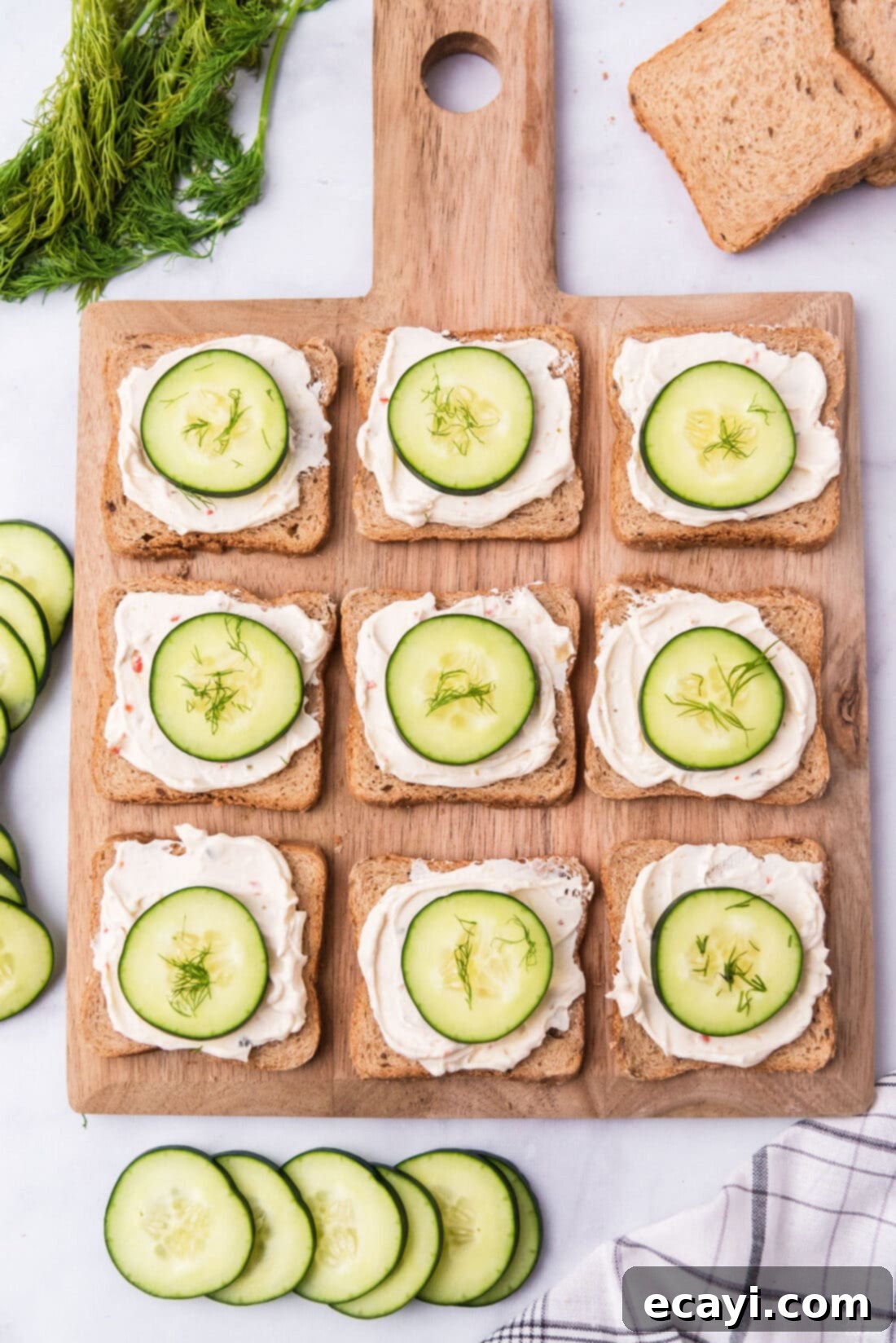 Delicate Cucumber Finger Sandwiches 7 An inviting arrangement of open-faced mini cucumber sandwiches displayed on a elegant wood board, highlighting their simple beauty.