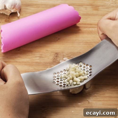 21 Kitchen Gadgets You'll Reach For Daily 10 A garlic press mincer shown in use, efficiently mincing garlic cloves with minimal effort and mess.