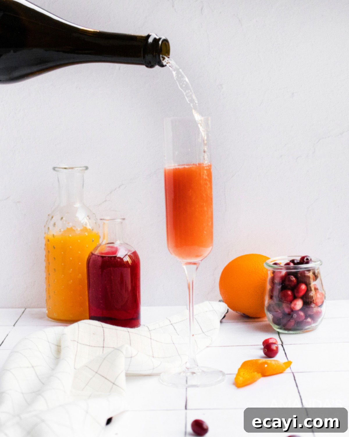 Sparkling Cranberry Mimosa 5 Topping off a cranberry and orange juice base with sparkling wine in a champagne flute