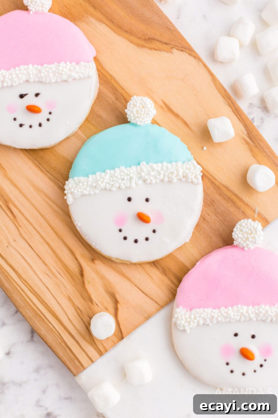 Sweet & Simple Decorated Cookies 10 Charming snowman sugar cookies with colorful hats, rosy cheeks, and mini M&M noses, arranged on a rustic cutting board.
