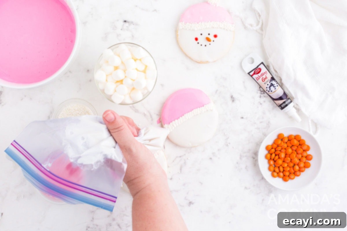 Sweet & Simple Decorated Cookies 14 A hand piping a white squiggle of frosting onto a cookie, dividing the pink hat from the white face.