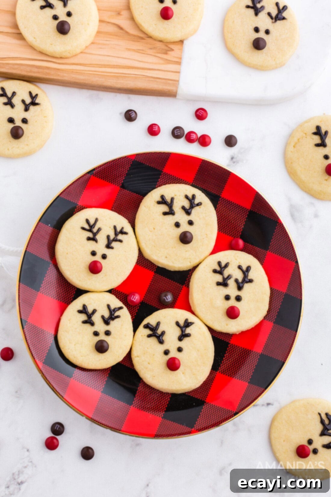 Sweet & Simple Decorated Cookies 22 A plate filled with adorable reindeer sugar cookies, each with black gel antlers, eyes, and a colorful mini M&M nose.