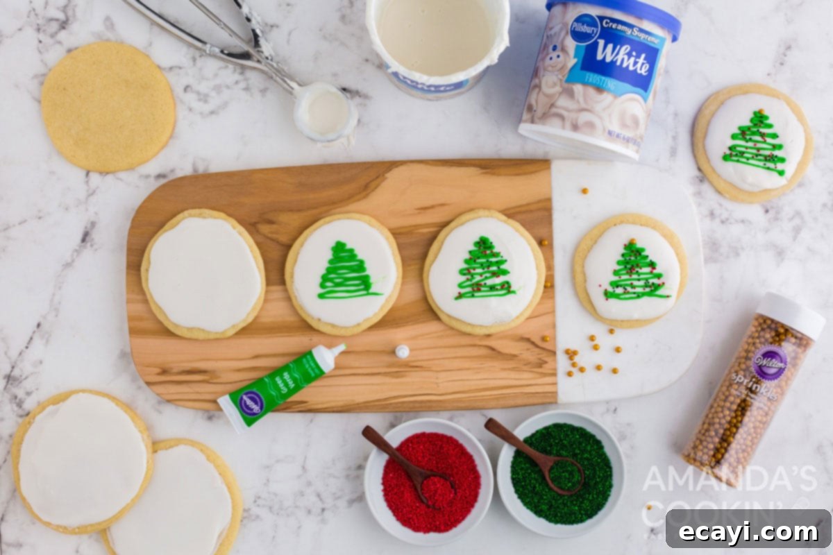 Sweet & Simple Decorated Cookies 7 A hand adding green Christmas tree designs with a decorator gel pen onto white iced sugar cookies.