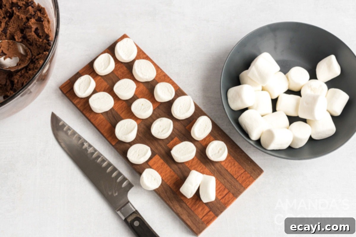 Cozy Cocoa Cookies 12 Regular-sized marshmallows cut in half on a cutting board, ready to be placed on the cookies.