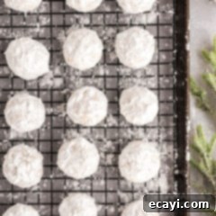 Snowball Cookies 16 Freshly baked snowball cookies cooling on a wire rack, covered in powdered sugar