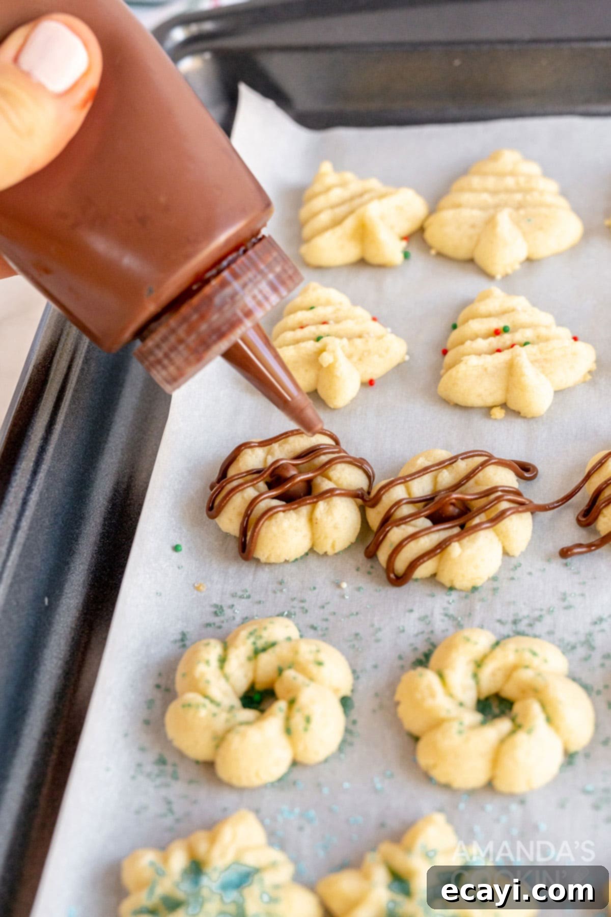 Spritz Cookies 12 A close-up of a cooled Spritz cookie being elegantly drizzled with melted chocolate, enhancing its appeal.