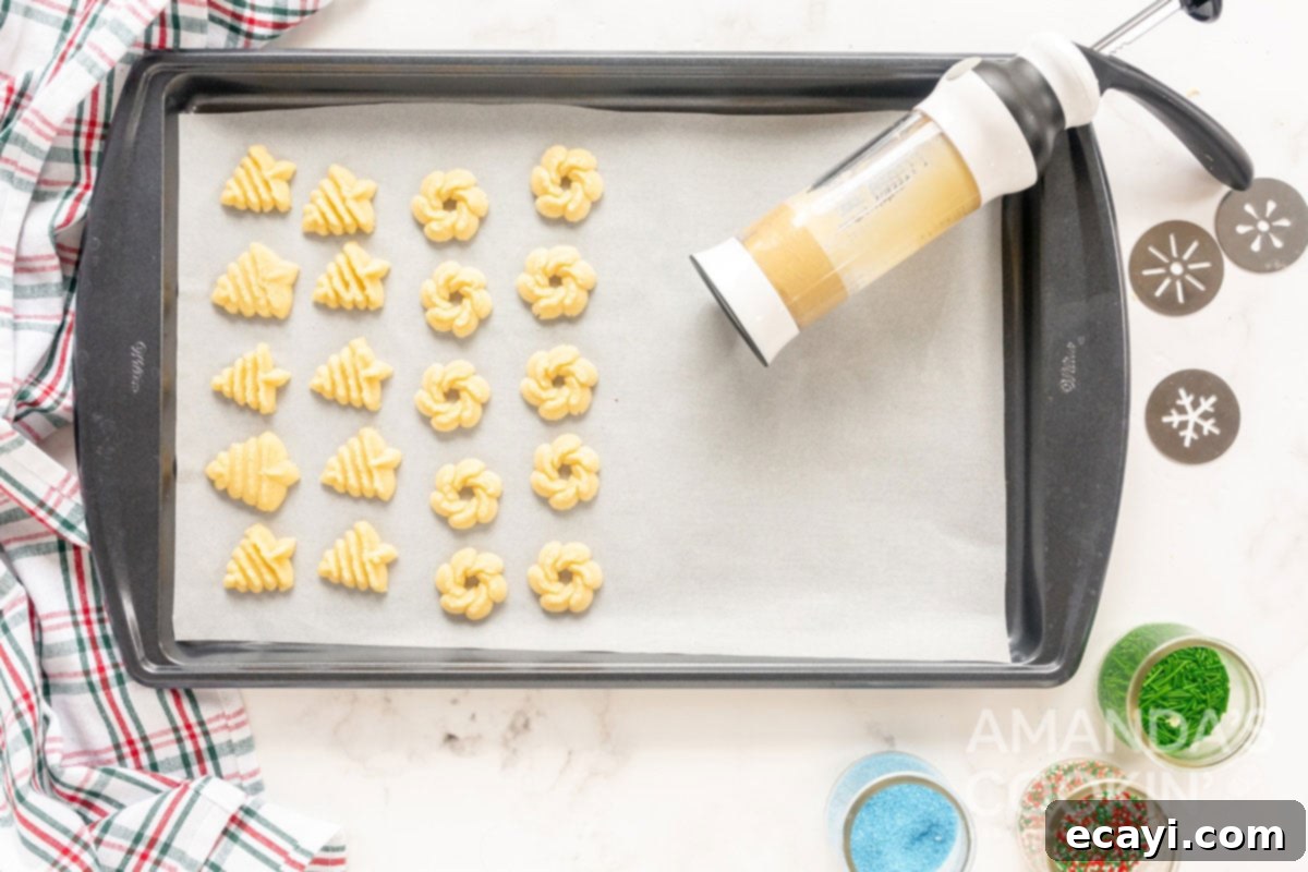 Spritz Cookies 9 Freshly pressed Spritz cookies neatly arranged on a baking sheet, displaying their intricate festive designs before baking.