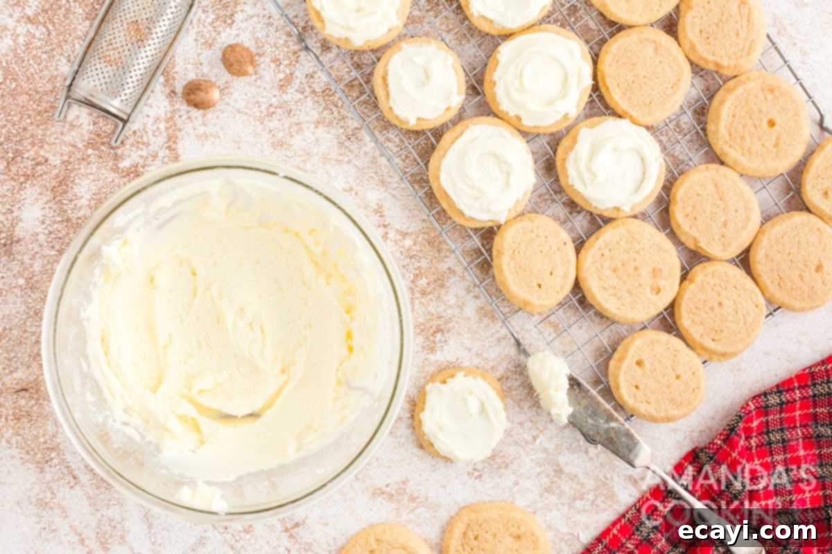 Velvet Eggnog Cookies 12 Hands frosting freshly baked eggnog cookies with creamy white frosting