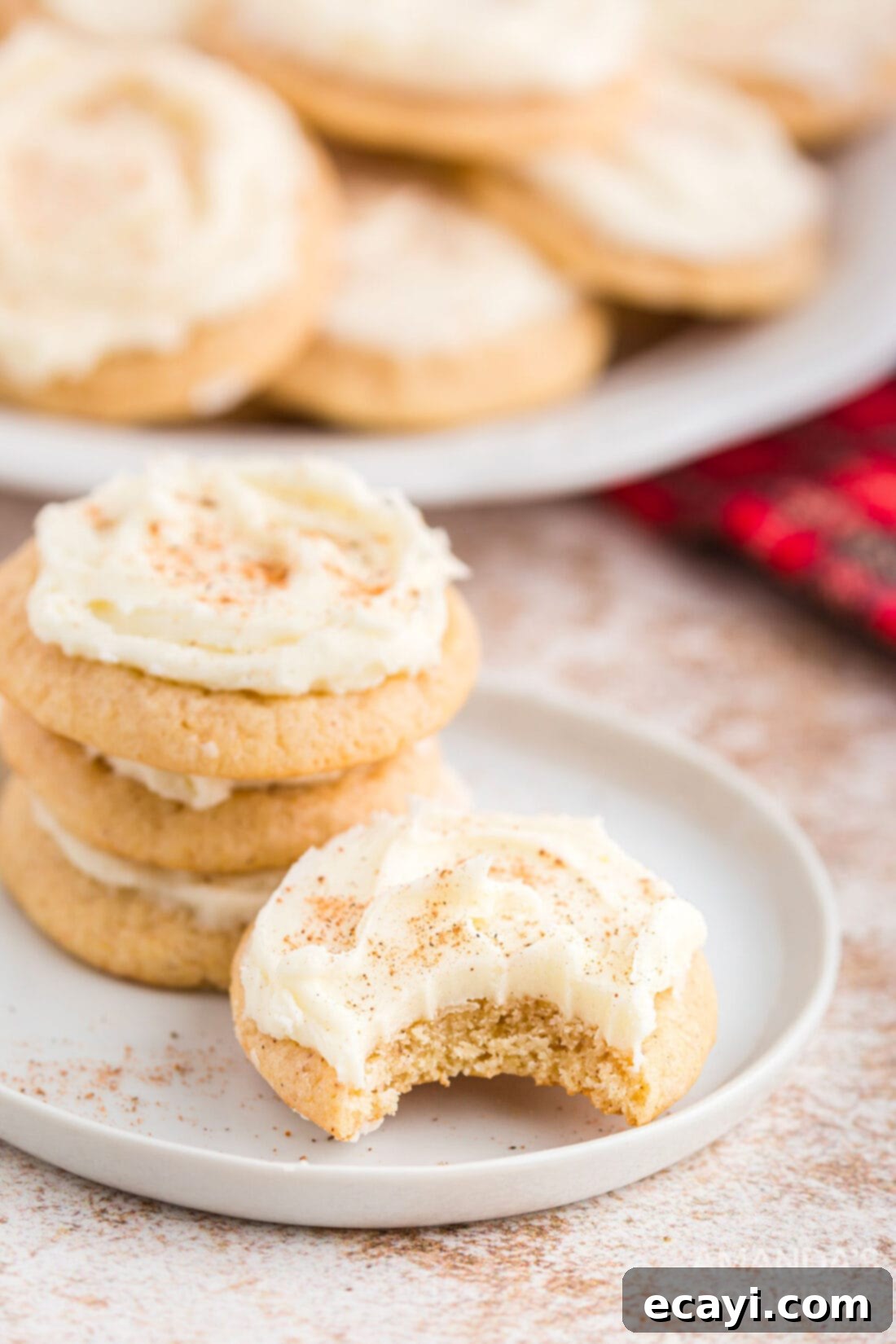 Velvet Eggnog Cookies 3 Close-up of a partially eaten eggnog cookie with a bite taken out, showing its soft texture and creamy frosting