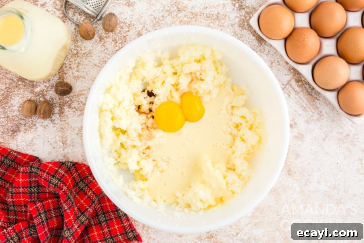 Velvet Eggnog Cookies 5 Egg yolks and vanilla being mixed with butter and sugar in a bowl for cookie dough