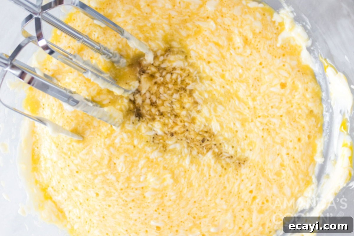Chewy Oat Delights 5 Mixing wet ingredients: softened butter, maple syrup, and eggs being combined in a large bowl with a hand mixer, forming a smooth batter