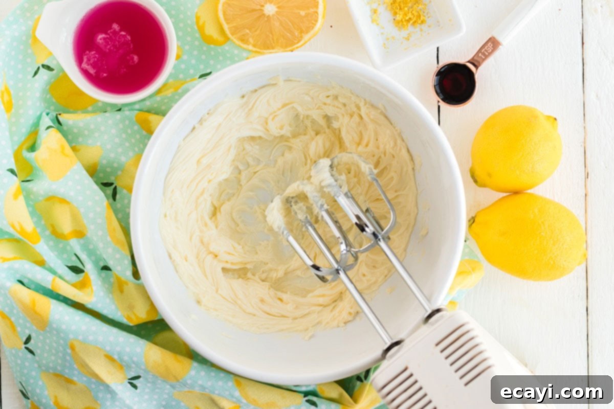 Sparkling Pink Lemonade Cake 10 A mixer beating softened butter in a bowl, creating a smooth and creamy base for the frosting.