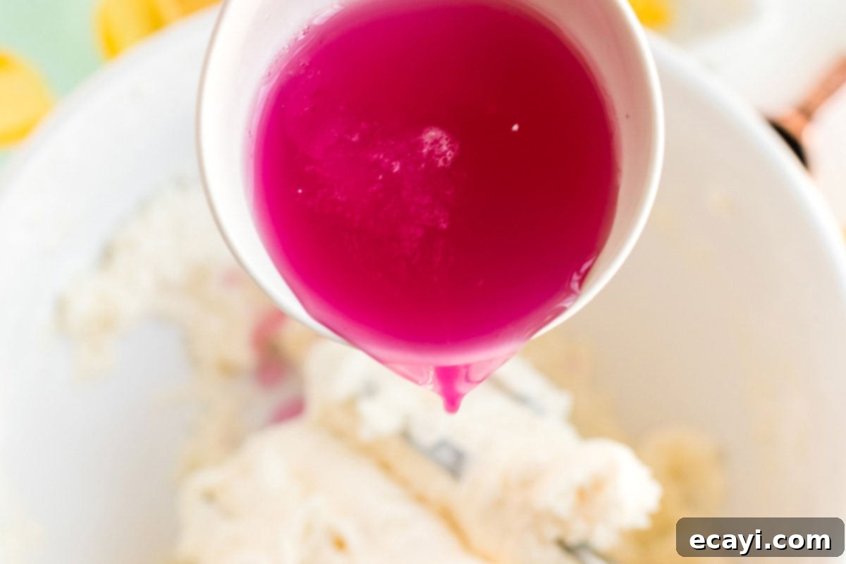 Sparkling Pink Lemonade Cake 11 A close-up shot of pink lemonade concentrate being added to a bowl of frosting ingredients, enhancing the flavor and color.