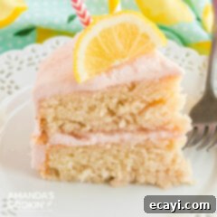 Sparkling Pink Lemonade Cake 14 A delectable slice of pink lemonade cake, elegantly topped with a thin slice of fresh lemon, ready for enjoyment.