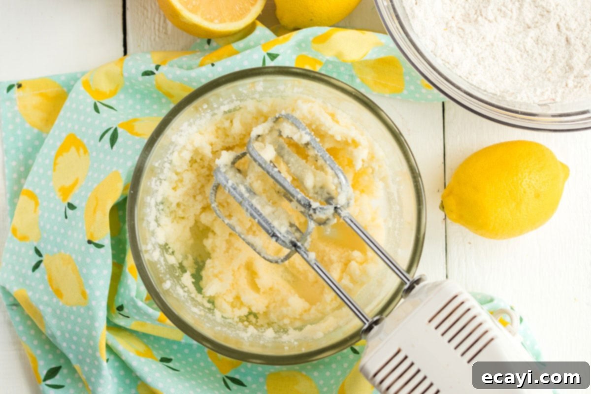 Sparkling Pink Lemonade Cake 7 A stand mixer vigorously combining softened butter and lemon-infused sugar in a bowl, creating a light and fluffy mixture.