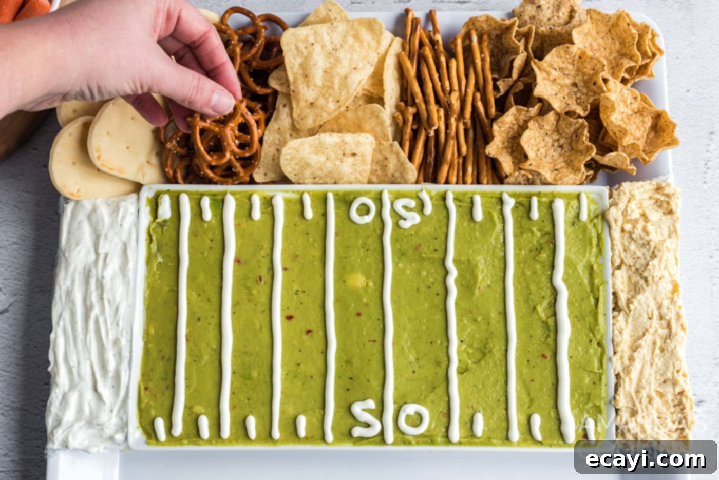 Game Day Grazing Platter 7 A hand reaches for a pretzel from the abundant selection of dippers beautifully arranged around the football party tray.