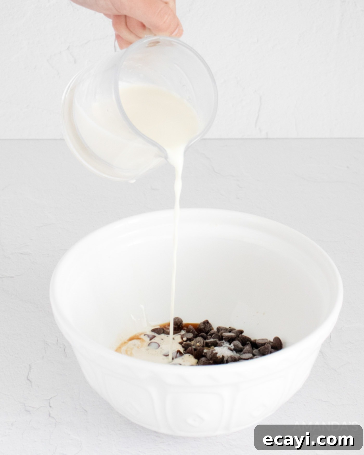 Decadent Mocha Truffles 5 Warm heavy cream being poured into a bowl containing chopped chocolate, espresso, butter, vanilla, and salt, ready to be whisked into a smooth mixture.