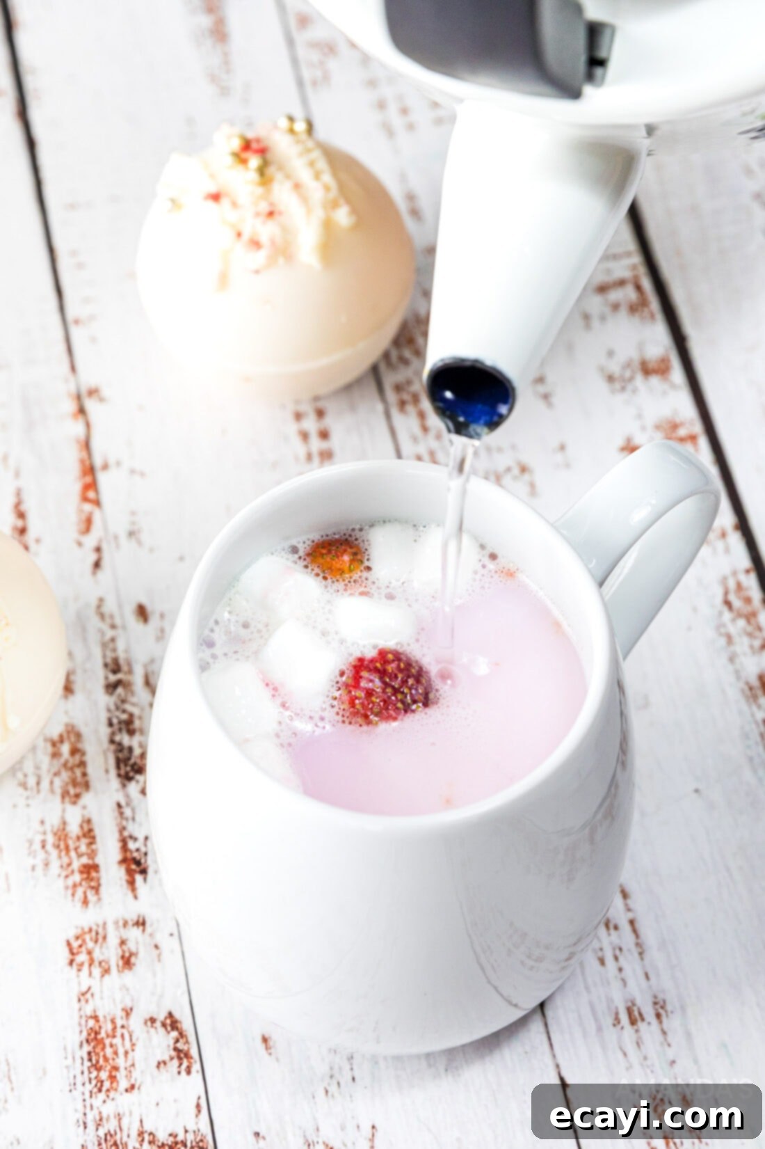 Dreamy Strawberry White Chocolate Hot Cocoa Bombs 15 Pouring steaming hot milk into a mug with a strawberry white chocolate hot cocoa bomb, beginning the magical melting process.