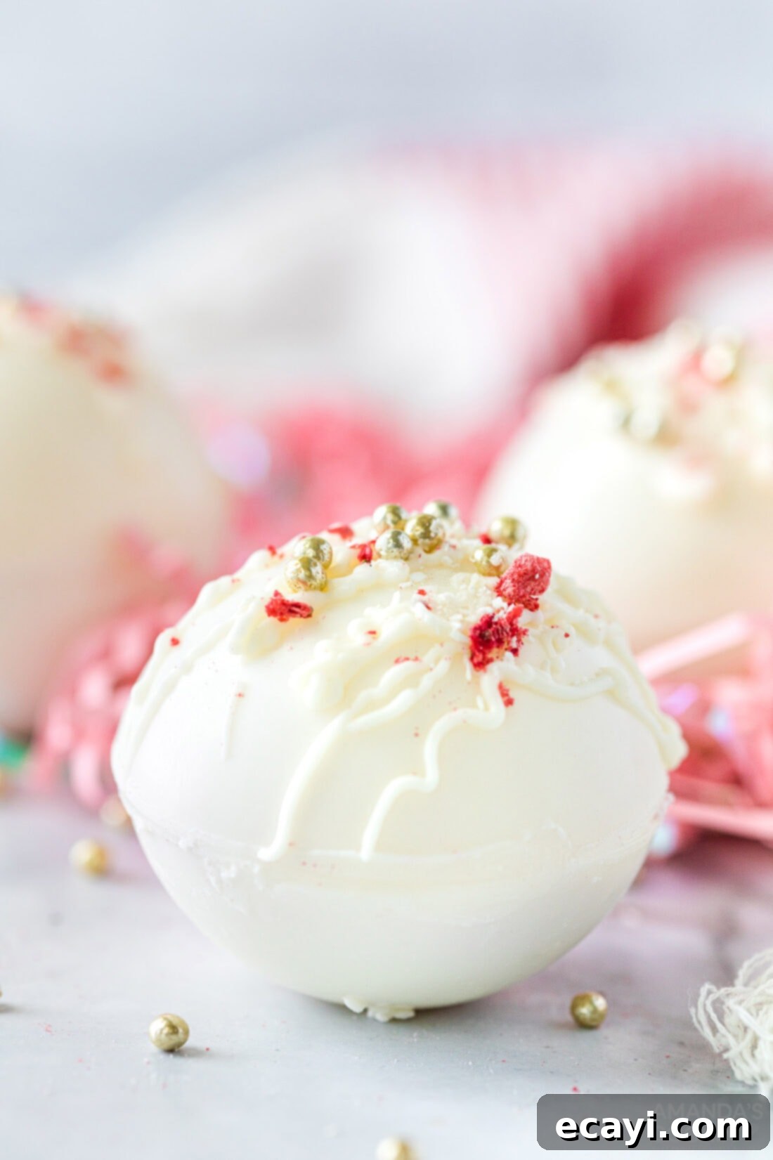 Dreamy Strawberry White Chocolate Hot Cocoa Bombs 16 A close-up shot of beautifully decorated strawberry white chocolate hot cocoa bombs, adorned with white chocolate drizzles and strawberry dust, showcasing their artisanal charm and delicious appeal.